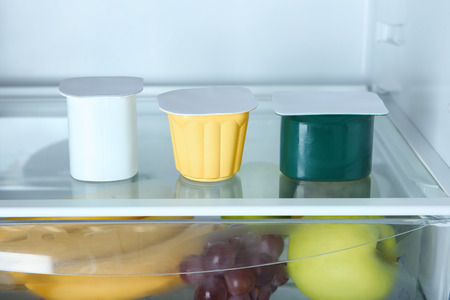 Plastic cups with yogurt in refrigeratorの写真素材