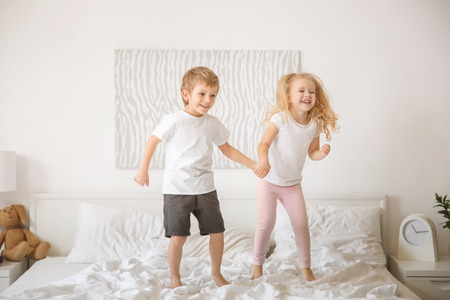 Cute children having fun on bed togetherの写真素材