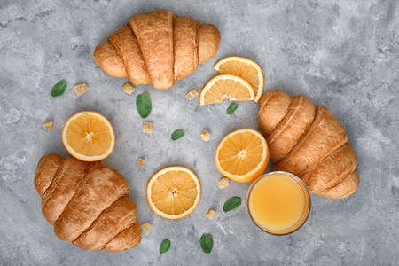 Tasty croissants with glass of orange juice and fruit on tableの写真素材