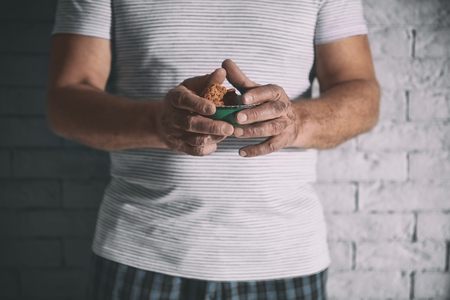Poor man holding bowl with bread on brick wall backgroundの写真素材