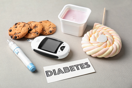 Composition with word "Diabetes", sweets and digital glucometer on light backgroundの写真素材