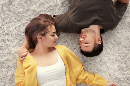 Cute young lovely couple lying on carpet at homeの写真素材