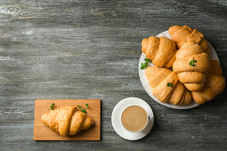 Delicious croissants with cup of coffee on wooden tableの写真素材