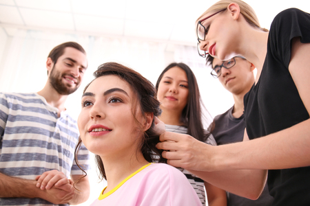 Professional hairdresser and trainees working with client in salon. Apprenticeship conceptの写真素材