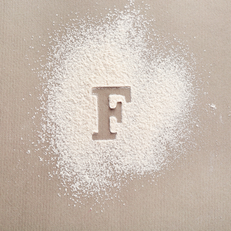 Silhouette of letter F on scattered flourの写真素材