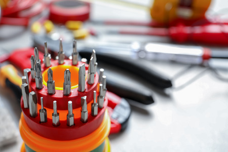 Screwdriver bit set and blurred electrical tools on background