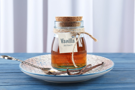 Plate with glass jar of vanilla extract on wooden tableの写真素材