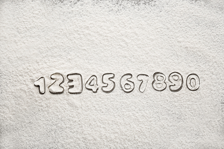 Silhouettes of Arabic numerals on scattered flourの写真素材