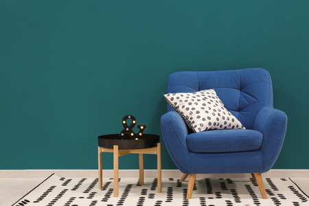 Trendy living room interior with comfortable armchair against shaded spruce wallの写真素材