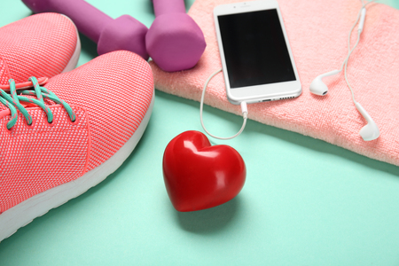 Gym stuff, phone and red heart on color background. Cardio training conceptの写真素材