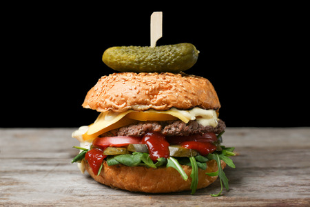 Tasty burger on table against dark backgroundの写真素材