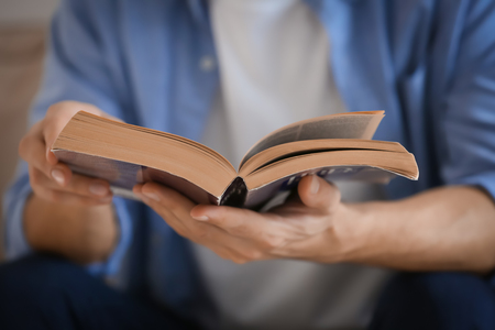 Religious young man reading Bible at home, closeupの写真素材