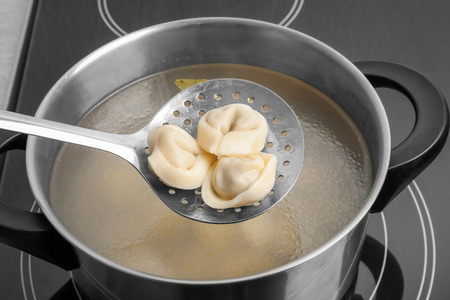 Cooked dumplings on skimmer over saucepanの写真素材