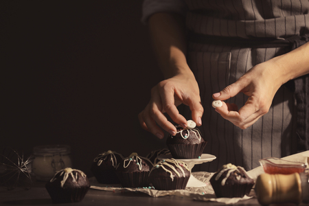Woman decorating tasty cupcake at tableの写真素材