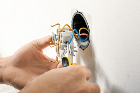 Electrician repairing socket on light wall