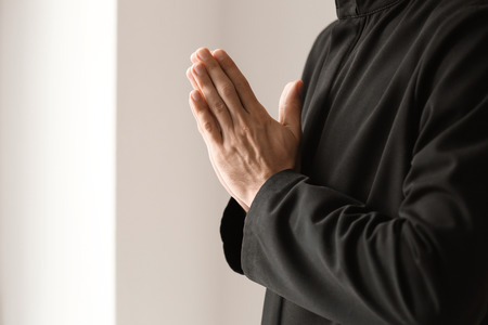 Young priest praying to God indoors