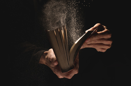 Priest with old Bible on black background, closeupの写真素材