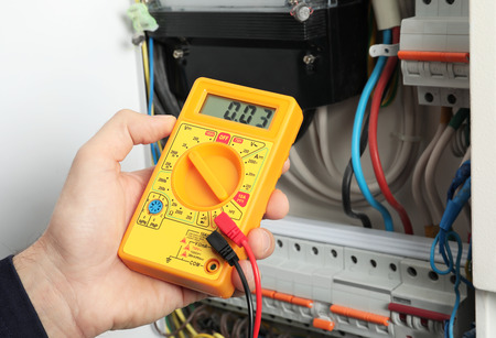 Young electrician measuring voltage in distribution board, closeupの写真素材