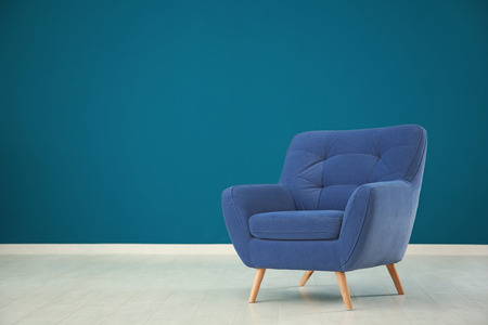 Comfortable armchair against color wall in empty roomの写真素材