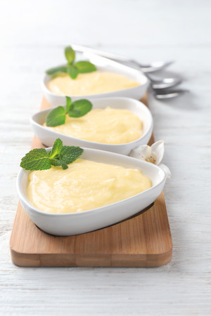 Ceramic dishes with vanilla pudding on wooden boardの写真素材