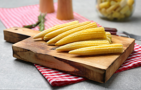 Wooden board with fresh young baby corn on tableの写真素材