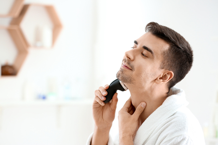 Handsome young man shaving in bathroomの写真素材