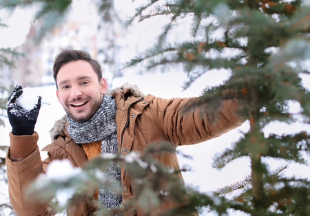Handsome man near fir tree in park on winter vacation