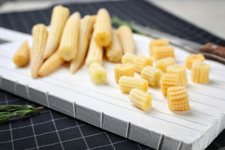 White cutting board with fresh young baby corn on table, closeupの写真素材