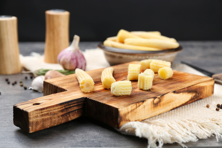 Wooden board with fresh young baby corn on tableの写真素材