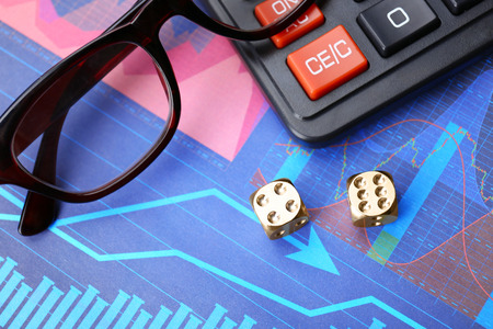 Dices, glasses and calculator on stock data graph. Finance trading conceptの写真素材