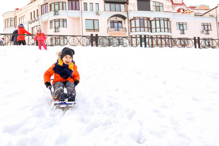 Cute boy sledding in snowy park on winter vacationの写真素材
