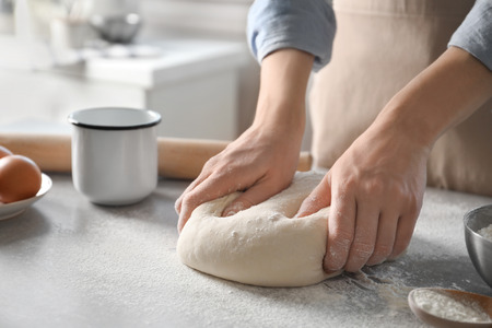 Woman kneading dough on table sprinkled with flourの写真素材