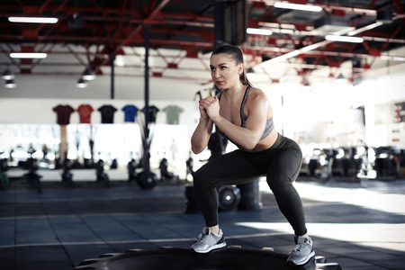 Young muscular woman training on heavy tire in gymの写真素材