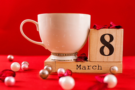 Wooden block calendar and cup of coffee on table. International Women's Day celebrationの写真素材