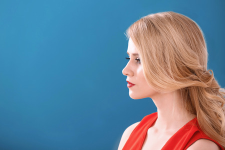 Young woman with beautiful curls on color background. Professional hairdresser's workの写真素材