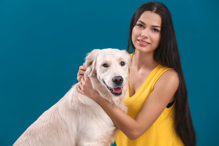 Young woman with dog on color background. Friendship between pet and ownerの写真素材