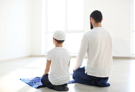 Muslim father and son praying together, indoorsの写真素材