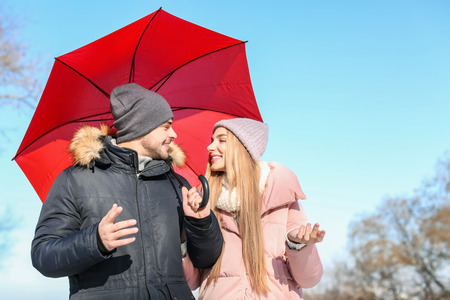Young romantic couple with bright umbrella on sunny winter dayの写真素材