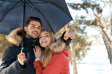 Young romantic couple with umbrella in parkの写真素材