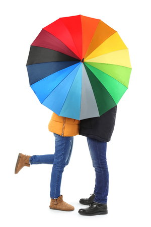 Young romantic couple with colorful umbrella on white backgroundの写真素材