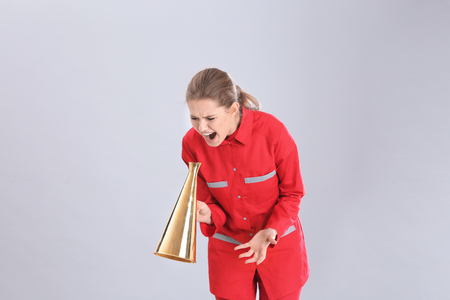 Young female emergency doctor shouting into megaphone on grey backgroundの写真素材