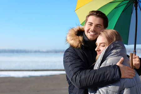 Young romantic couple with colorful umbrella on river bankの写真素材