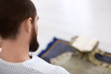 Young Muslim man praying, indoors