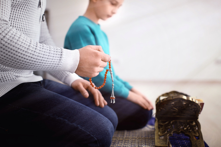 Muslim father and son praying together, indoorsの写真素材