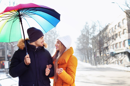Young romantic couple with colorful umbrella on city streetの写真素材