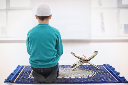 Little Muslim boy praying, indoors