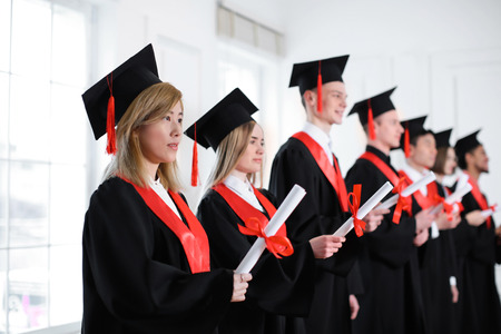 Students in bachelor robes with diplomas indoors. Graduation dayの写真素材