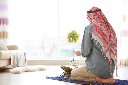 Muslim man praying on rug at homeの写真素材
