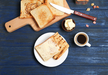 Plate and wooden board with toasted bread on table