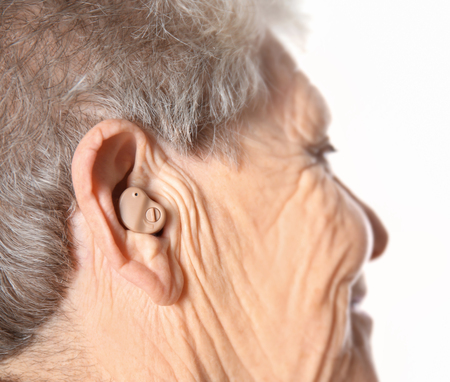 Senior woman with hearing aid on white backgroundの写真素材